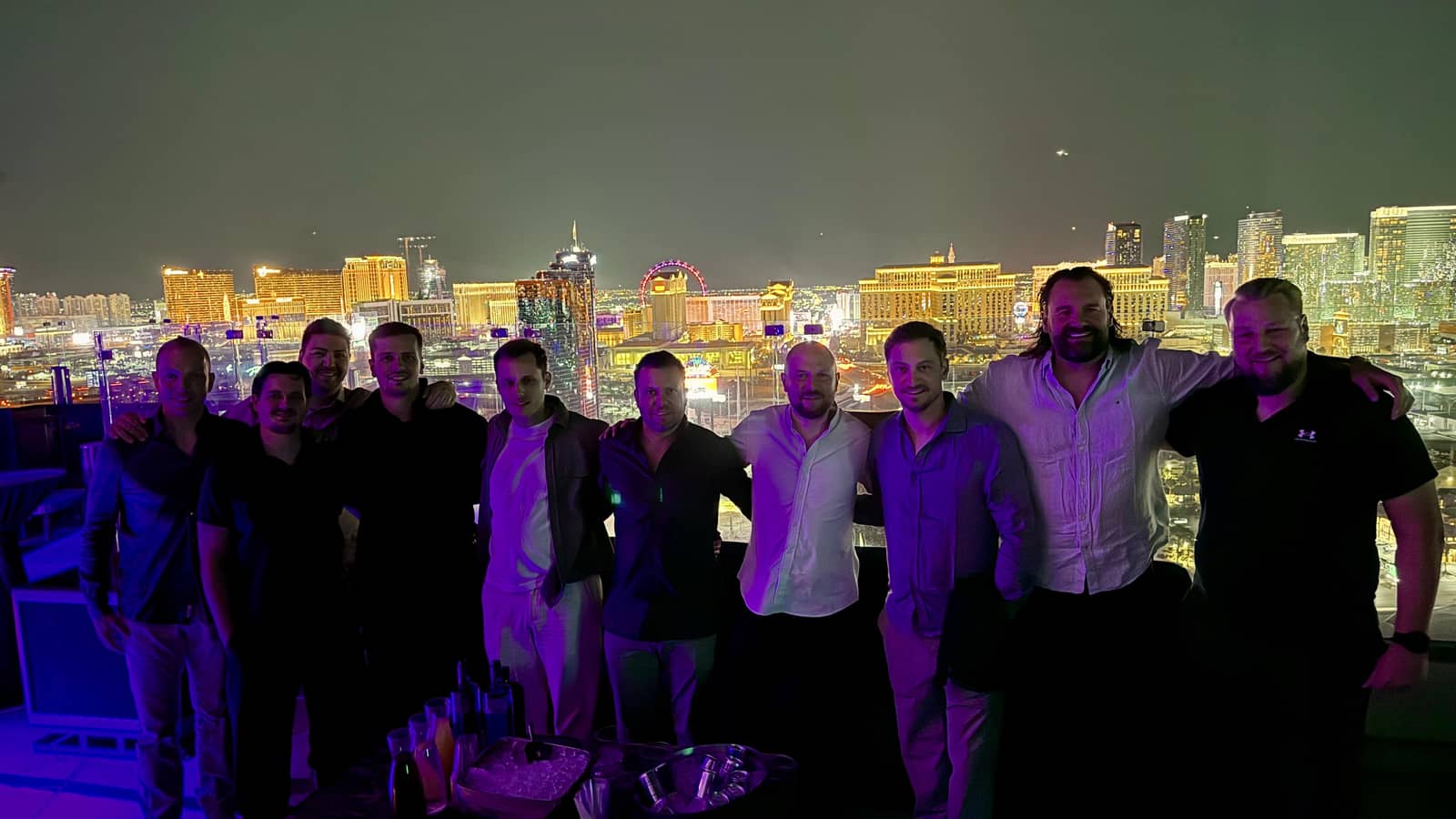 A bachelor party group of ten guys at a Ghostbar table with the Las Vegas Strip skyline behind them